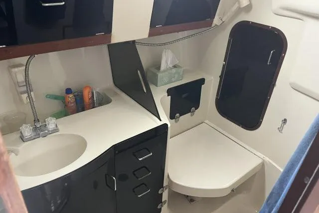 Slide: The Image of 1995 Hunter 336 yacht bathroom with sink, storage, and porthole window. - 14