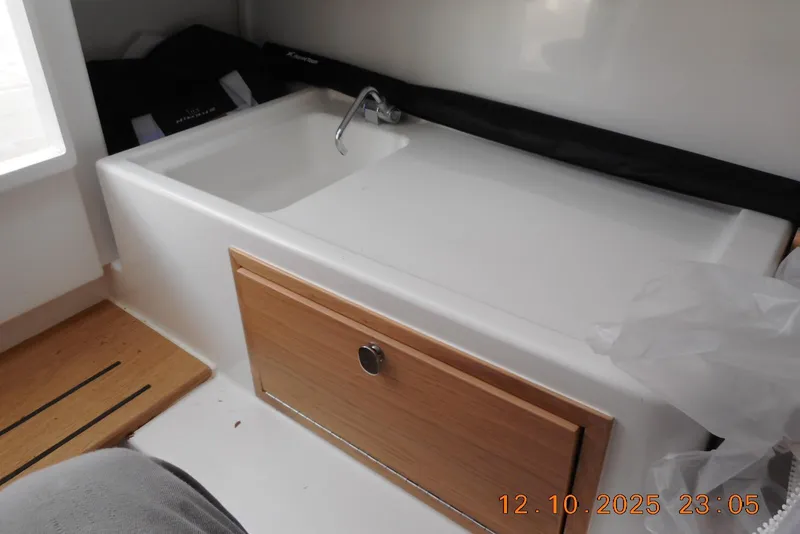 Slide: The Image of Interior of 2025 Nimbus Tender 8 boat featuring a compact sink and wooden cabinet. - 21