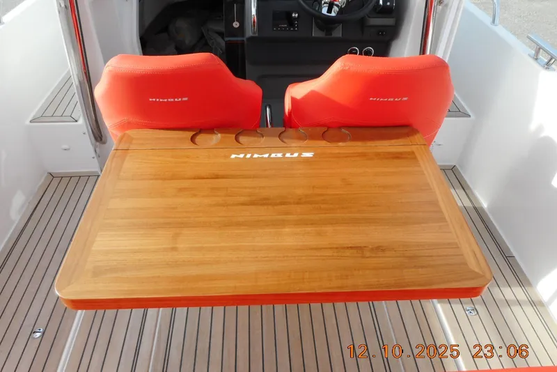 Slide: The Image of 2025 Nimbus Tender 8 boat interior with red seats and wooden table. - 24