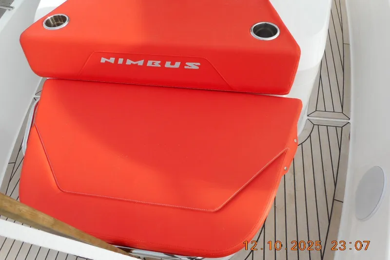 Slide: The Image of Red seating on 2025 Nimbus Tender 8 boat with cup holders, wooden deck visible. - 25