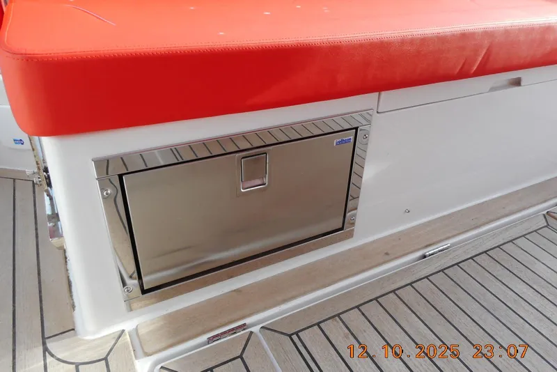 Slide: The Image of Red cushioned seat on 2025 Nimbus Tender 8 boat with stainless steel storage. - 26