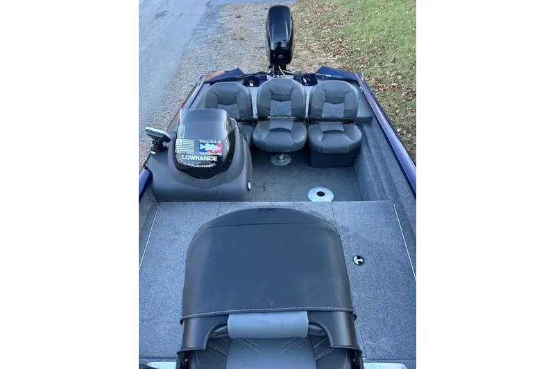 Slide: The Image of 2020 Tracker Pro Team 175 TF boat interior with seating and motor, parked on grass. - 13