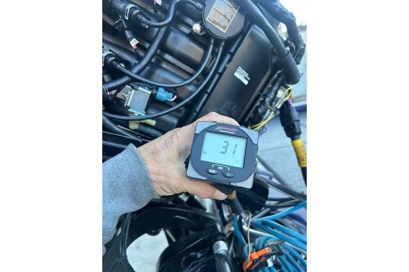 Slide: The Image of Hand holding a digital gauge near Tracker Pro Team 175 TF engine, 2020 model. - 8
