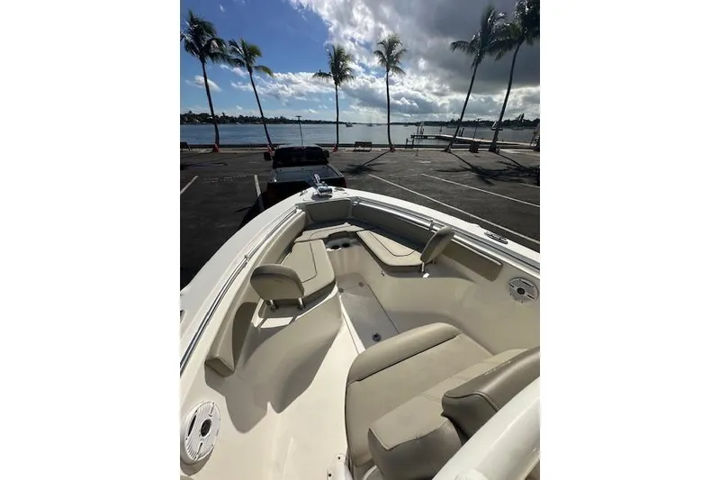 Slide: The Image of 2022 Key West 239 FS boat interior with seating, parked near waterfront under palm trees. - 7