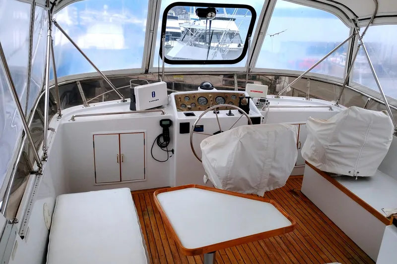 Slide: The Image of 1985 Ocean Alexander Custom Aft Deck Motoryacht helm with covered seating and wooden flooring. - 16