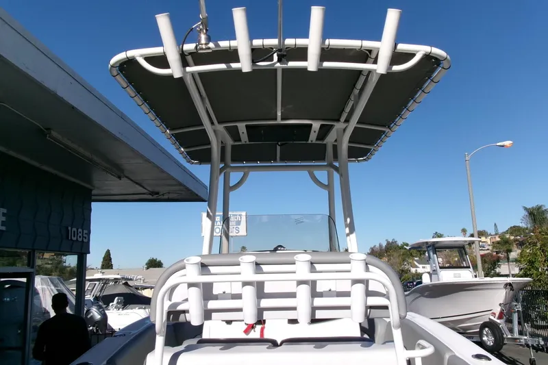 Slide: The Image of 2023 NauticStar 2102 Legacy boat with T-top, displayed outdoors under clear blue sky. - 24