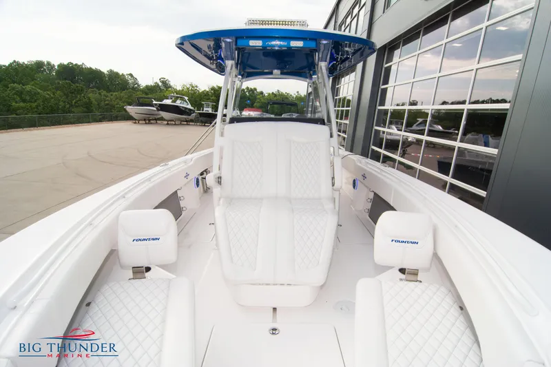 Slide: The Image of 2023 Fountain 34 Center Console boat with white seating, docked near showroom. - 23
