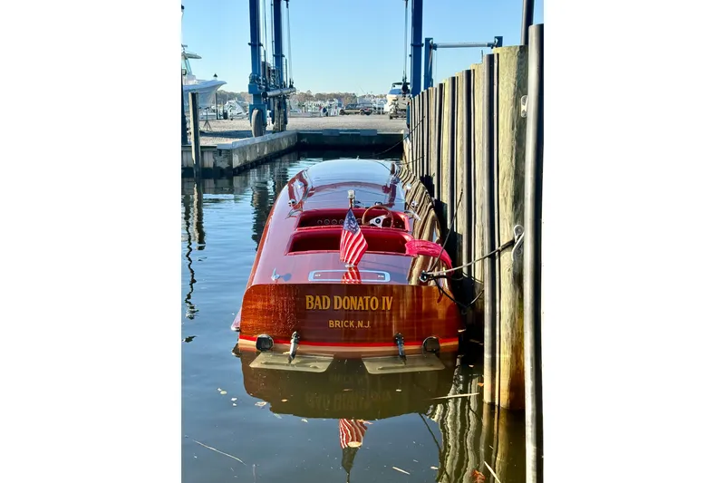 Slide: The Image of Custom 1998 30 Gentleman's Racer boat docked, featuring polished wood and American flag. - 16