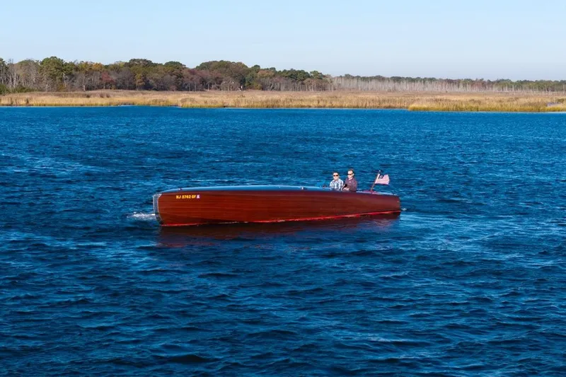 Slide: The Image of Custom 30 Gentleman's Racer boat from 1998 cruising on a serene blue lake. - 5