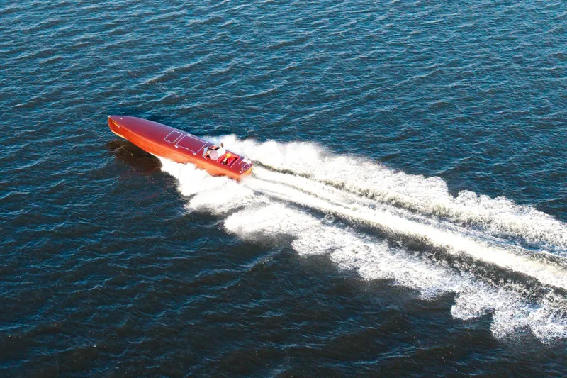 Slide: The Image of Custom 30 Gentleman's Racer boat from 1998 speeding on open water, aerial view. - 7