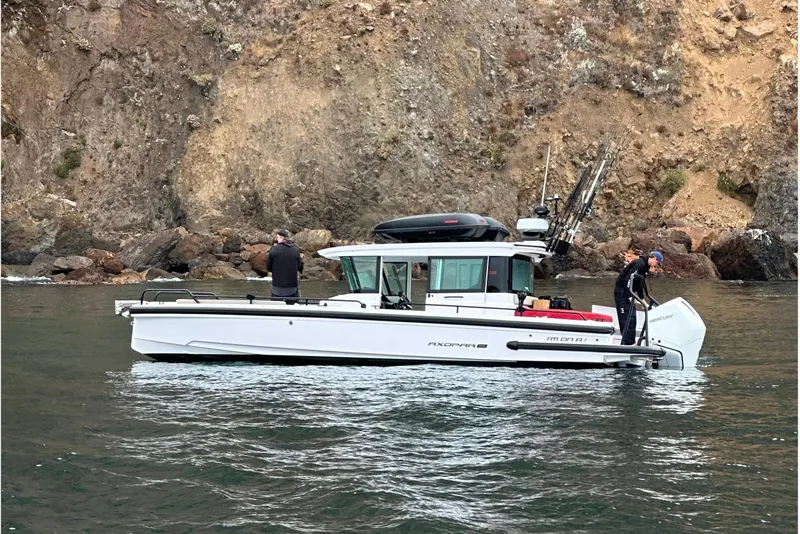 Slide: The Image of 2023 Axopar 28 Aft Cabin with Brabus Trim, moored near coastal hillside buildings. - 4