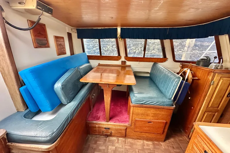 Slide: The Image of Interior of a 1970 CAL 46 Cruiser with blue seating and wooden table. - 11