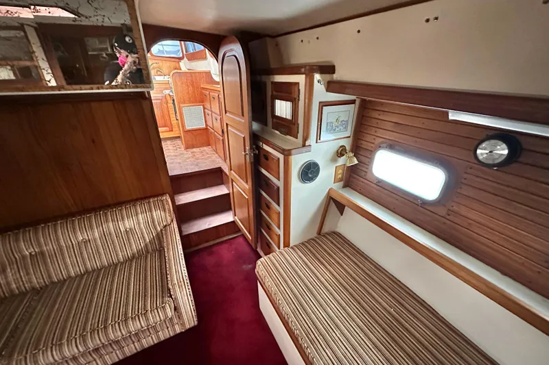 Slide: The Image of Interior of a 1970 CAL 46 Cruiser yacht with wood paneling and striped seating. - 17