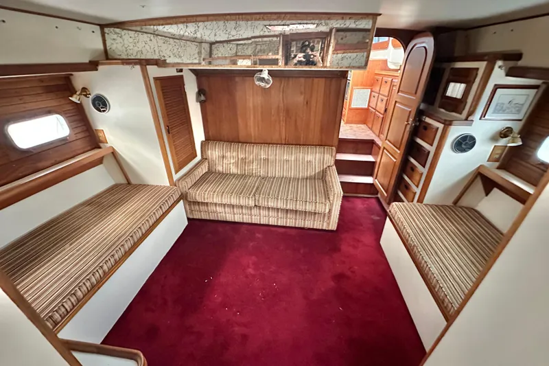 Slide: The Image of 1970 CAL 46 Cruiser interior with striped seating, wood paneling, and red carpet. - 19
