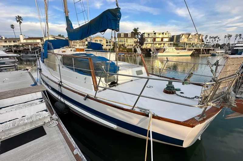 Slide: The Image of 1970 CAL 46 Cruiser sailboat docked in a marina with waterfront homes. - 2