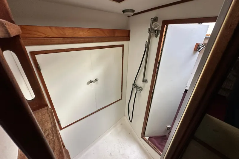 Slide: The Image of 1970 CAL 46 Cruiser interior shower area with wooden accents and storage cabinet. - 21