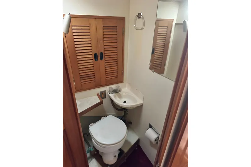 Slide: The Image of Compact bathroom in 1970 CAL 46 Cruiser with wooden cabinets and white fixtures. - 22