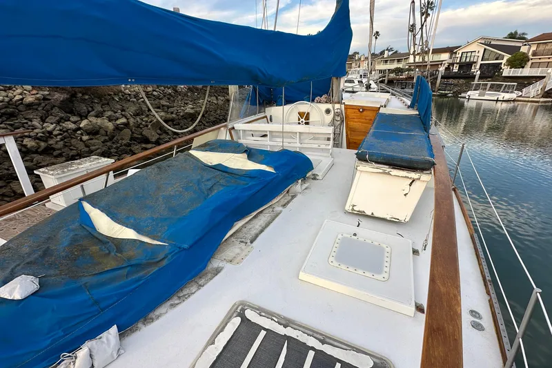 Slide: The Image of 1970 CAL 46 Cruiser sailboat with blue covers docked in a marina. - 3