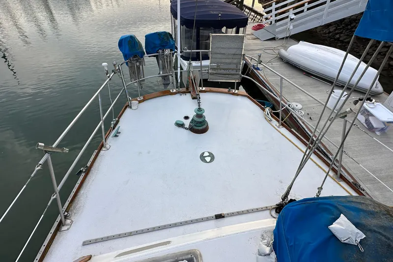 Slide: The Image of 1970 CAL 46 Cruiser sailboat deck at marina, featuring winches and covered equipment. - 31