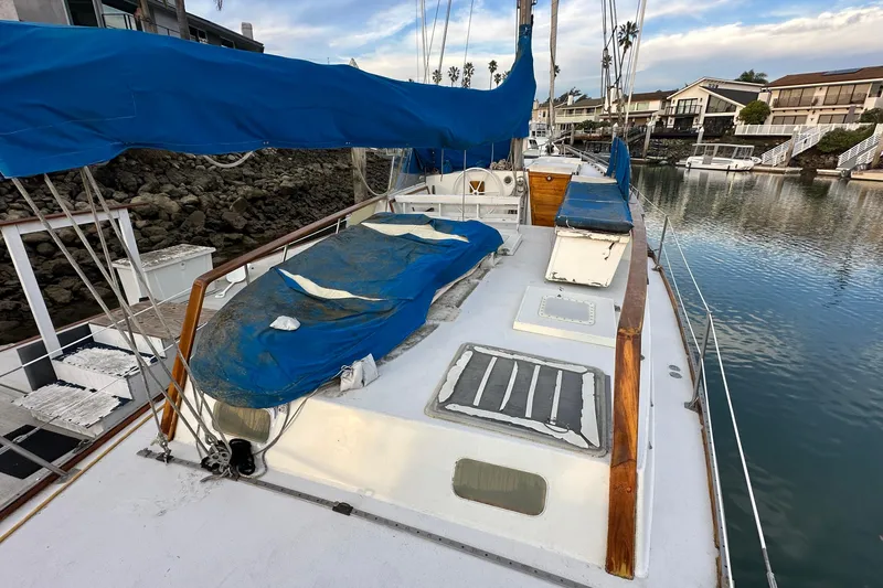 Slide: The Image of 1970 CAL 46 Cruiser sailboat docked, featuring blue covers and wooden accents. - 32