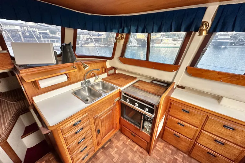 Slide: The Image of 1970 CAL 46 Cruiser kitchen with wood cabinetry, dual sink, and stove, overlooking marina. - 6