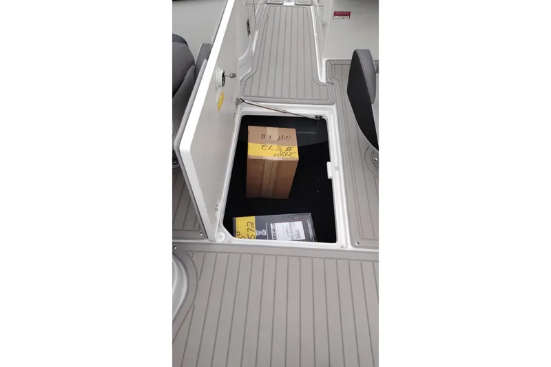Slide: The Image of Open storage compartment on 2026 Crownline 288 SS boat deck with boxes inside. - 45