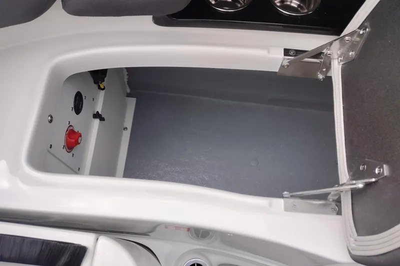 Slide: The Image of Open storage compartment in 2026 Crownline 288 SS boat, featuring secure latch and cup holders. - 53