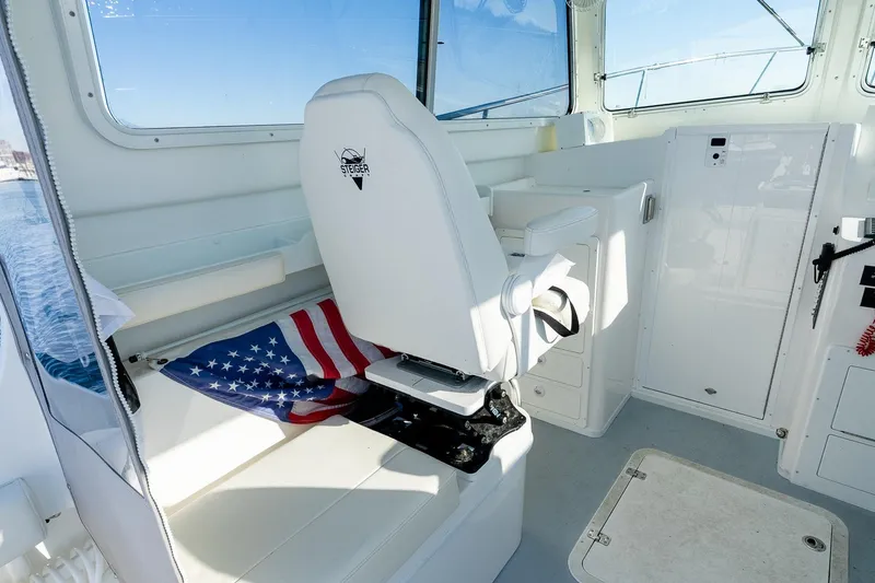 Slide: The Image of 2024 Steiger Craft 31 Fisherman interior with captain's chair and American flag. - 28