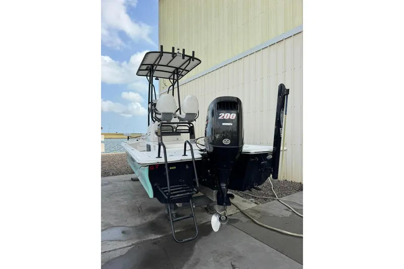 Slide: The Image of 2017 Blue Wave 2200 STL boat with 200 HP engine, docked near a building. - 3