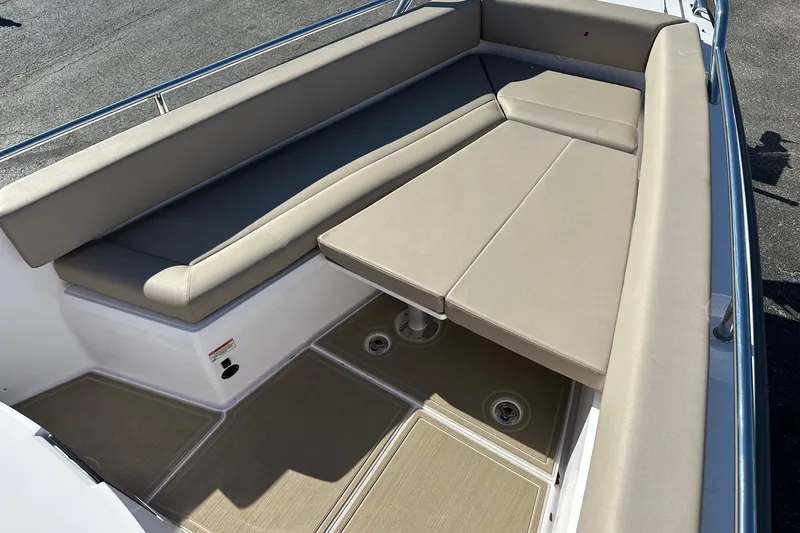 Slide: The Image of 2022 Axopar 28 CABIN boat interior with beige cushioned seating and table. - 12
