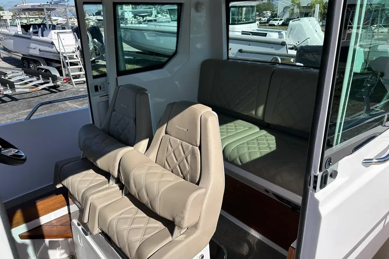 Slide: The Image of 2022 Axopar 28 CABIN interior with beige quilted seating and large windows. - 21