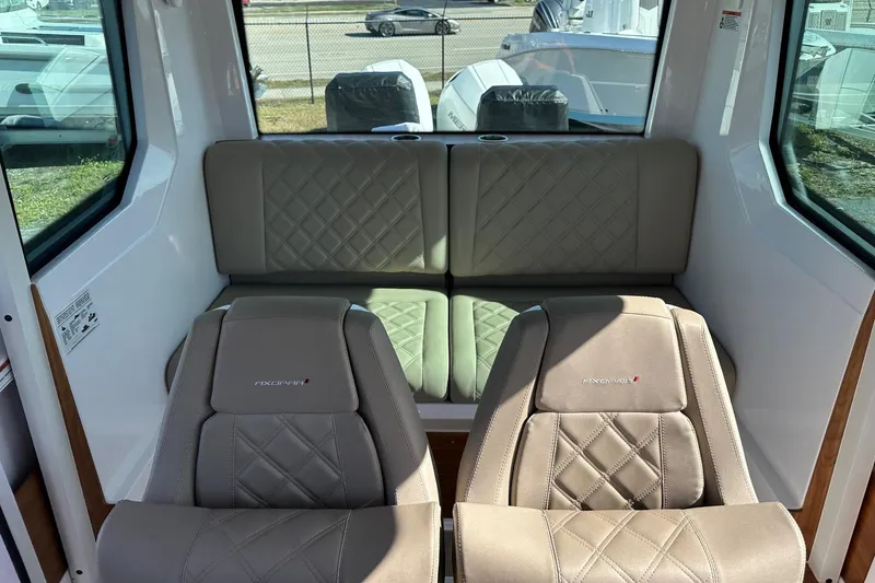 Slide: The Image of 2022 Axopar 28 CABIN interior with beige quilted seats and large windows. - 32
