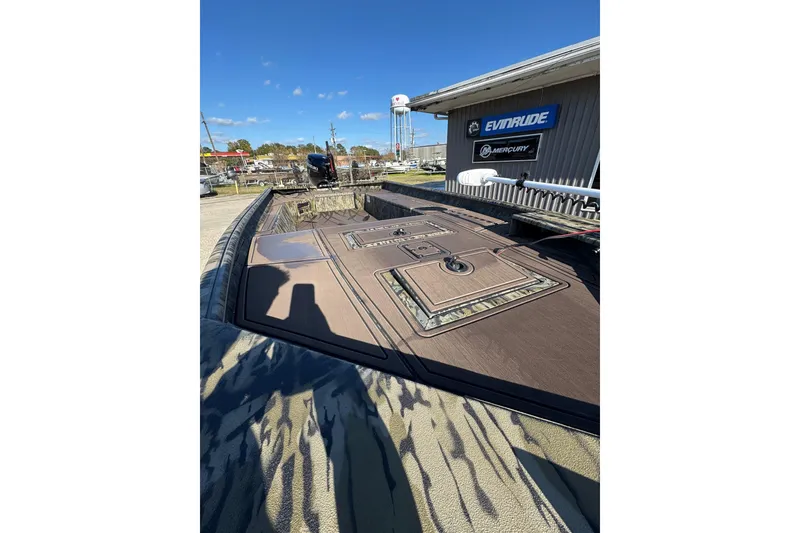 Slide: The Image of 2026 SeaArk 1960 Slayer Pro boat with camo design, displayed outdoors near dealership signs. - 12