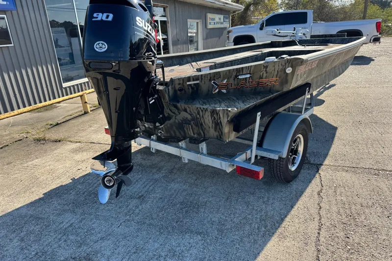 Slide: The Image of 2026 SeaArk 1960 Slayer Pro boat on trailer with Suzuki 90 engine, parked outside. - 6