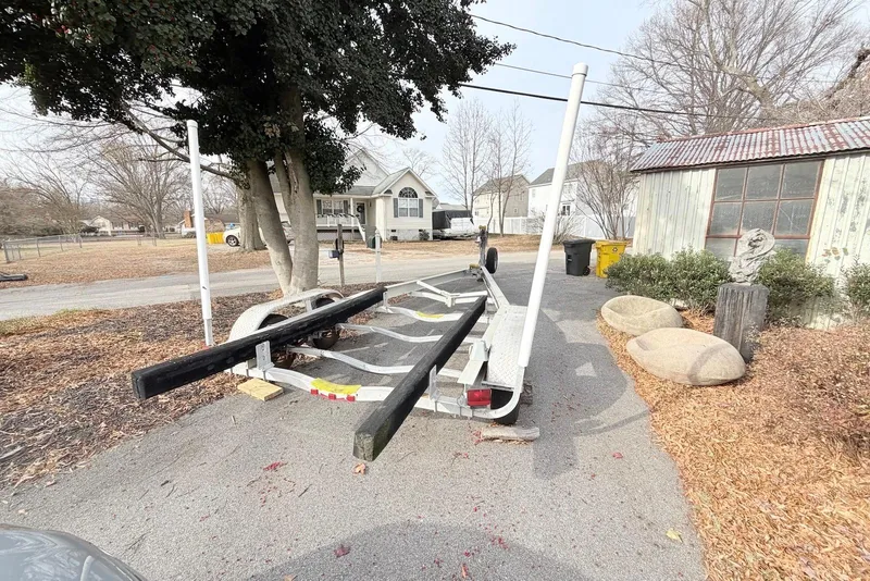 Slide: The Image of Empty boat trailer parked on driveway, surrounded by trees and houses. - 12