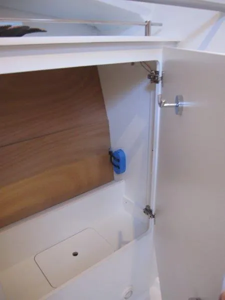 Slide: The Image of 2024 Jeanneau 380 interior storage compartment with wooden panel and white door. - 15