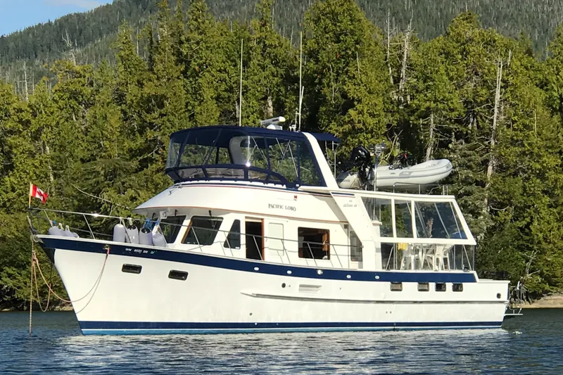 The Image of 1994 DeFever Double Cabin yacht on calm water, surrounded by lush forest. - 0