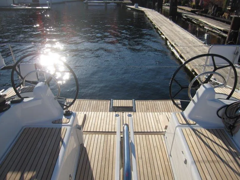 Slide: The Image of 2024 Jeanneau 380 yacht cockpit with dual steering wheels, docked by the water. - 36