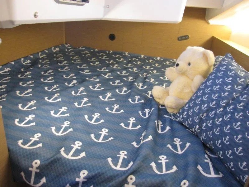 Slide: The Image of Jeanneau 380 2024 cabin with anchor-themed bedding and a teddy bear. - 9