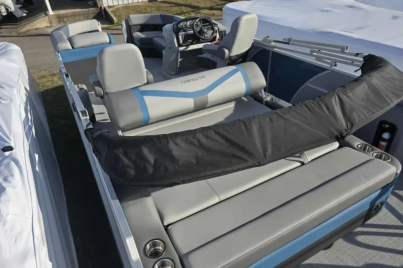 Slide: The Image of 2026 Trifecta 24ULCS3 pontoon boat with gray and blue seating, steering console, and cup holders. - 16