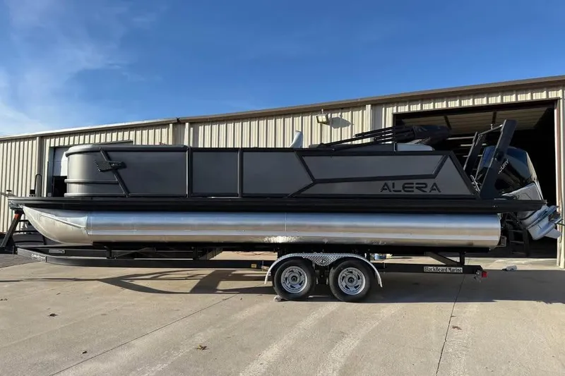 The Image of 2026 Alera M 25Q pontoon boat on trailer outside a warehouse. - 0