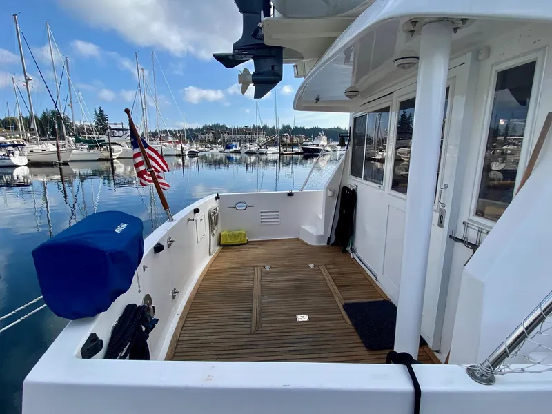 Slide: The Image of 1999 Ocean Alexander 510 Pilothouse at dock, featuring wooden deck and American flag. - 9