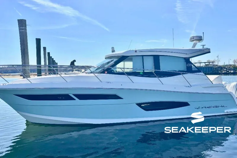The Image of 2022 Regal 38 XO yacht docked in sunny marina, featuring sleek design and Seakeeper logo. - 0