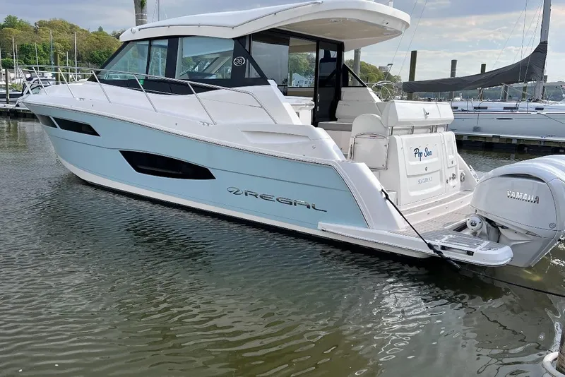Slide: The Image of 2022 Regal 38 XO yacht docked, featuring sleek design and Yamaha outboard engines. - 2