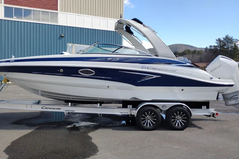 The Image of 2026 Crownline 260 XSS boat on trailer, blue and white design, parked outdoors. - 0