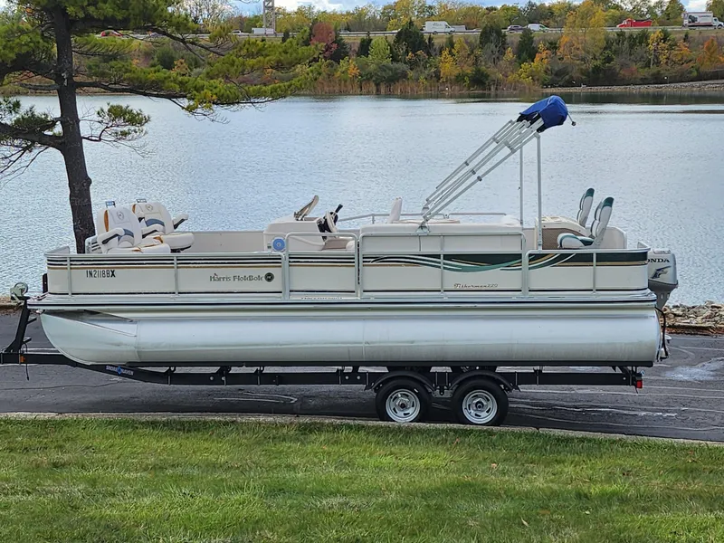 The Image of 2002 Harris FloteBote 220 Fisherman pontoon boat on trailer by a lake. - 0