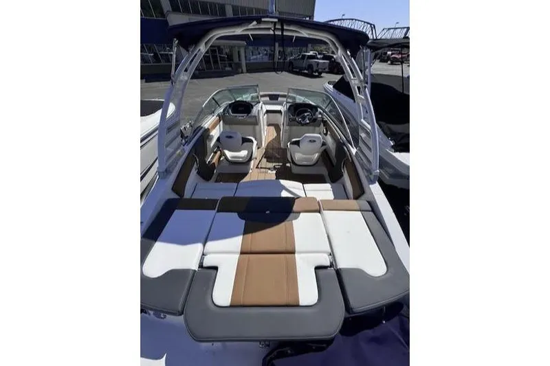 Slide: The Image of 2025 Chaparral 21 SSi boat interior with seating and steering wheel, docked outdoors. - 5