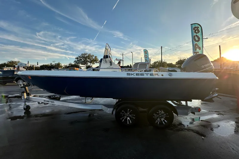 Slide: The Image of 2014 Skeeter SX2250 boat with Yamaha engine, parked on a trailer under a blue sky. - 8