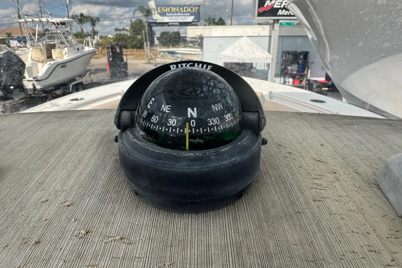 Slide: The Image of Compass on 2020 Sportsman Heritage 231 Center Console boat, docked with other vessels nearby. - 20