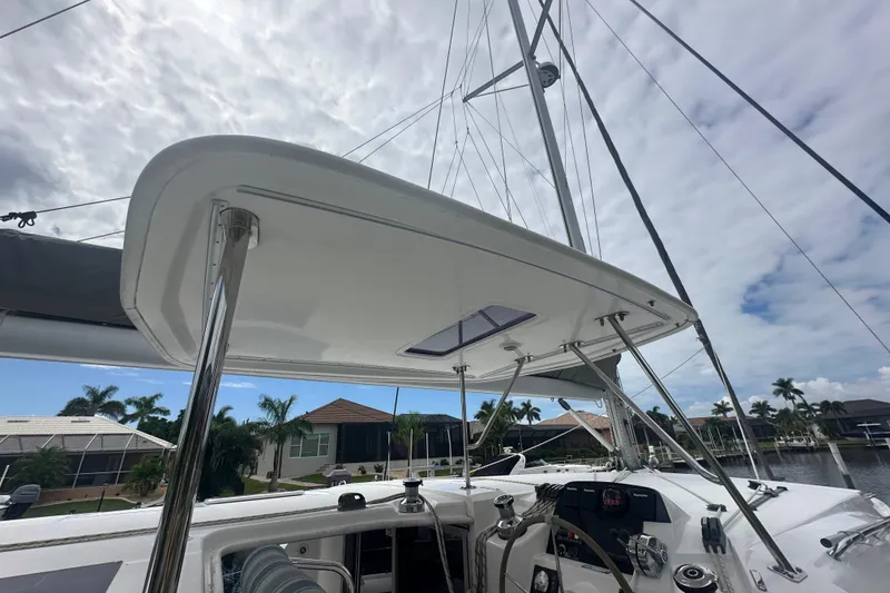 Slide: The Image of 2016 Leopard 44 catamaran cockpit with helm, under cloudy sky, docked near waterfront homes. - 49